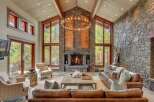 Experience luxurious mountain living in this stunning great room, featuring a grand stone fireplace and soaring vaulted ceilings with exposed beams.