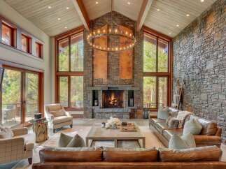 Experience luxurious mountain living in this stunning great room, featuring a grand stone fireplace and soaring vaulted ceilings with exposed beams.