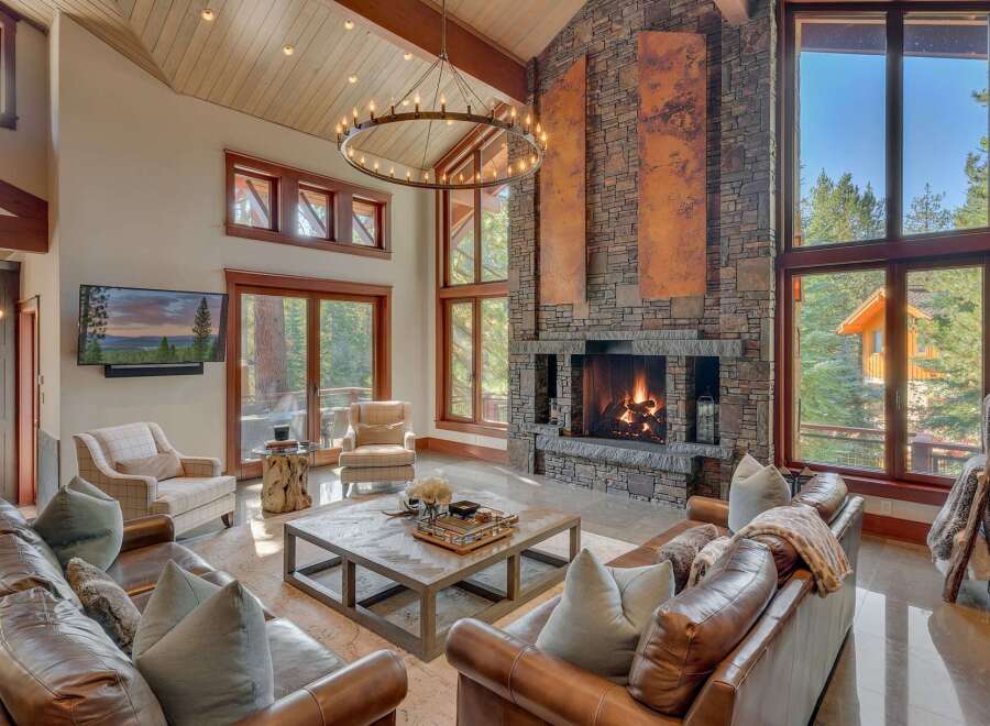 Experience luxurious mountain living in this stunning great room, featuring a grand stone fireplace and soaring vaulted ceilings with a statement chandelier.