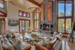 Experience luxurious mountain living in this stunning great room, featuring a grand stone fireplace and soaring vaulted ceilings with a statement chandelier.