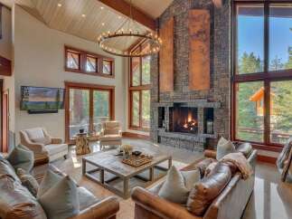 Experience luxurious mountain living in this stunning great room, featuring a grand stone fireplace and soaring vaulted ceilings with a statement chandelier.