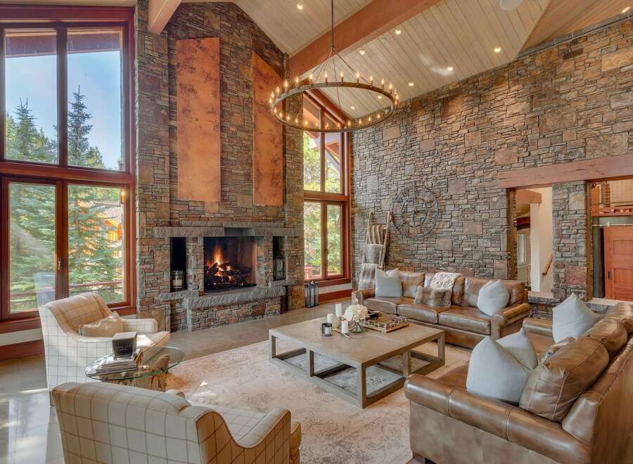 Experience rustic luxury in this stunning great room, featuring a grand stone fireplace and soaring vaulted ceilings with exposed wooden beams.