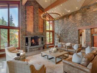 Experience rustic luxury in this stunning great room, featuring a grand stone fireplace and soaring vaulted ceilings with exposed wooden beams.