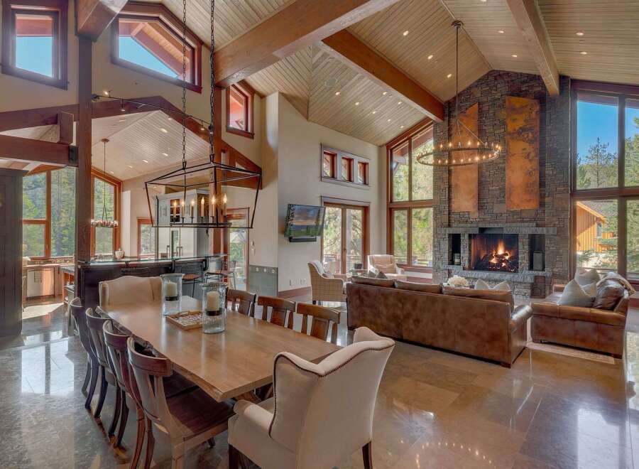 Experience luxurious mountain living in this stunning great room, featuring a soaring vaulted ceiling with exposed wooden beams and a grand stone fireplace.