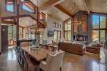Experience luxurious mountain living in this stunning great room, featuring a soaring vaulted ceiling with exposed wooden beams and a grand stone fireplace.