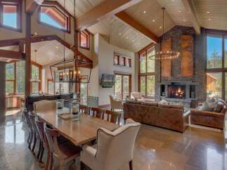 Experience luxurious mountain living in this stunning great room, featuring a soaring vaulted ceiling with exposed wooden beams and a grand stone fireplace.