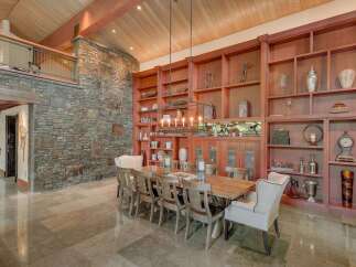 Experience rustic elegance in this stunning dining room, featuring a grand wooden dining table surrounded by plush chairs, perfect for hosting memorable gatherings.