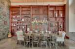 Experience rustic elegance in this spacious dining room, featuring a grand wooden bookshelf filled with decorative items and a charming 'Cabin' sign.