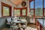 Enjoy breathtaking forest views from this charming kitchen nook, complete with a built-in banquette and a round glass-top table perfect for intimate meals.