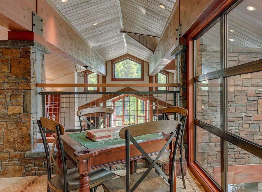 Experience rustic luxury in this stunning mountain home, featuring exposed wooden beams and a grand stone fireplace.