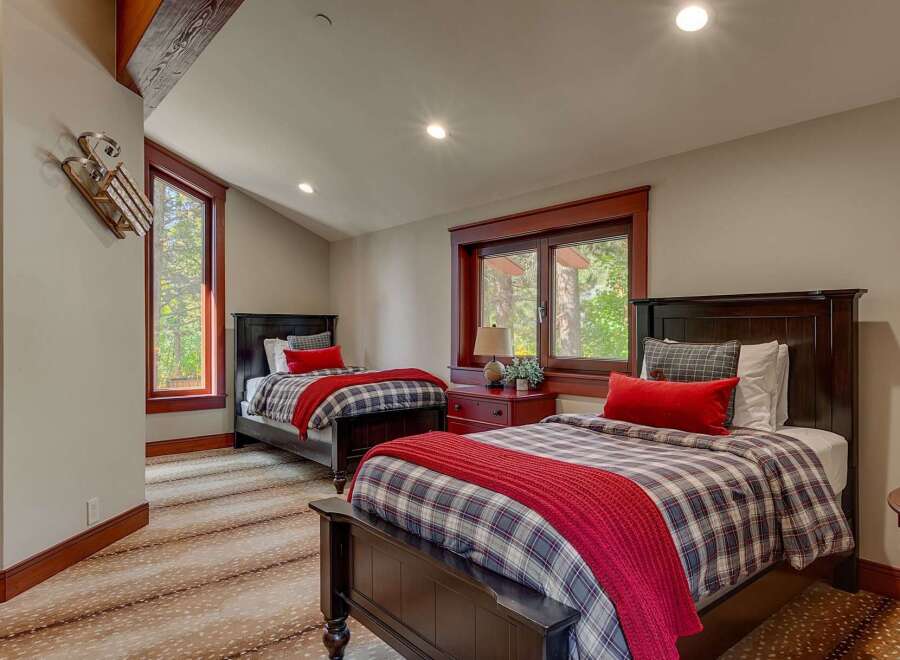 This charming bedroom features two dark wood twin beds adorned with cozy plaid bedding and vibrant red throws, perfect for a restful night's sleep.