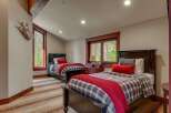 This charming bedroom features two dark wood twin beds adorned with cozy plaid bedding and vibrant red throws, perfect for a restful night's sleep.