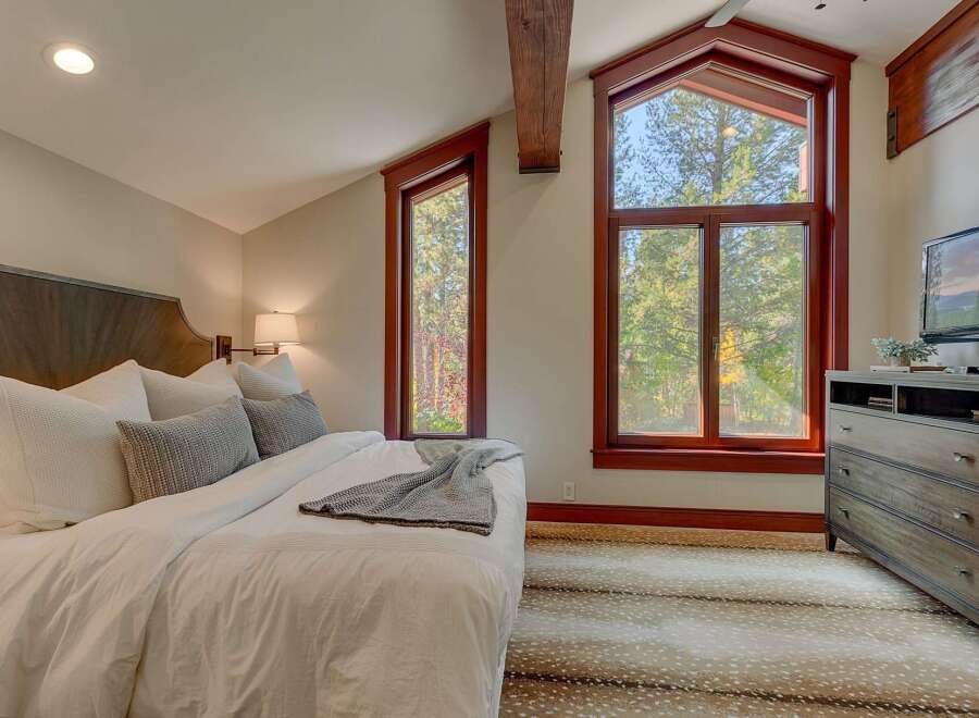 Experience rustic charm in this inviting bedroom, featuring a plush king-sized bed adorned with crisp white linens and decorative pillows.