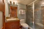 This bathroom features a modern vanity with a stone countertop and a sleek undermount sink, complemented by a large mirror with stylish vanity lighting.