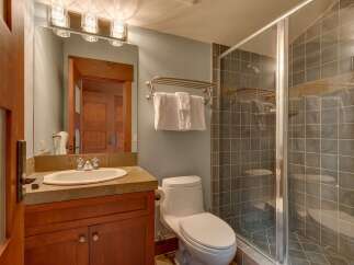 This bathroom features a modern vanity with a stone countertop and a sleek undermount sink, complemented by a large mirror with stylish vanity lighting.