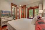 Experience ultimate comfort in this beautifully appointed bedroom, featuring a large flat-screen TV mounted on an antique dresser and direct access to a luxurious en-suite bathroom.