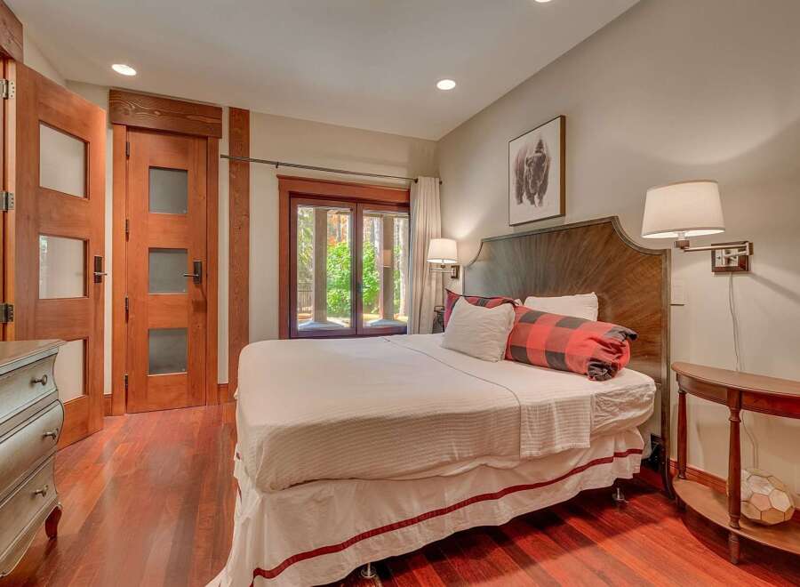 Experience rustic elegance in this charming bedroom, featuring a luxurious king-size bed adorned with buffalo plaid accents and plush white linens.