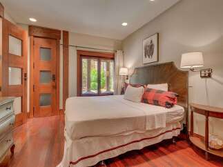 Experience rustic elegance in this charming bedroom, featuring a luxurious king-size bed adorned with buffalo plaid accents and plush white linens.