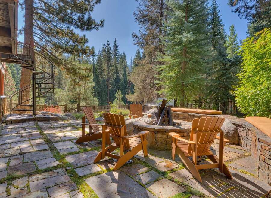 Experience the ultimate outdoor living with this stunning patio featuring a stone fire pit and comfortable Adirondack chairs, perfect for gathering with loved ones.