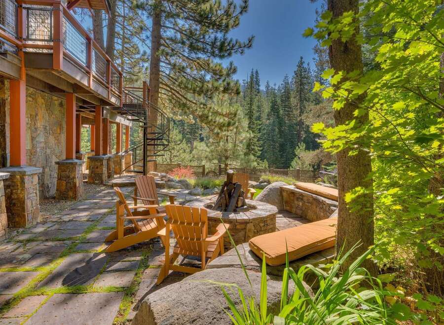 Experience the ultimate outdoor living with this stunning patio featuring a stone fire pit and comfortable Adirondack chairs, perfect for gathering with loved ones.