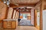 Experience rustic charm in this A-frame cabin featuring a cozy wood-paneled interior and a central wood-burning stove.