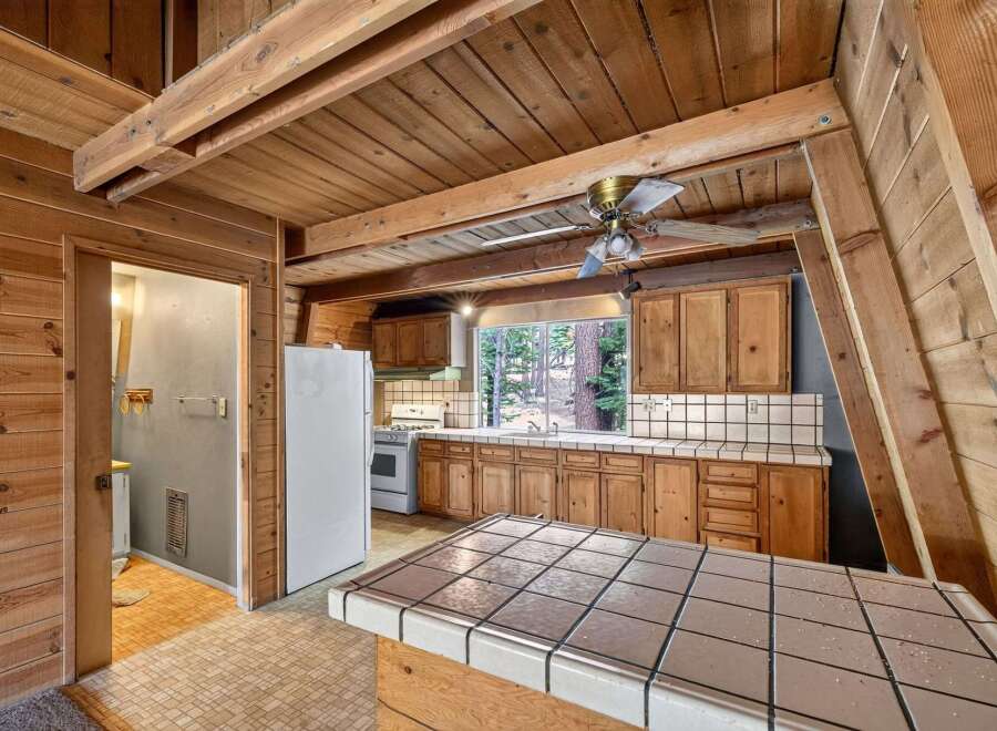Step into this charming A-frame kitchen, featuring warm wood paneling and exposed beams that create a cozy, rustic ambiance.