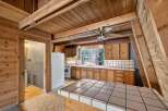 Step into this charming A-frame kitchen, featuring warm wood paneling and exposed beams that create a cozy, rustic ambiance.