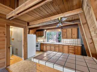 Step into this charming A-frame kitchen, featuring warm wood paneling and exposed beams that create a cozy, rustic ambiance.
