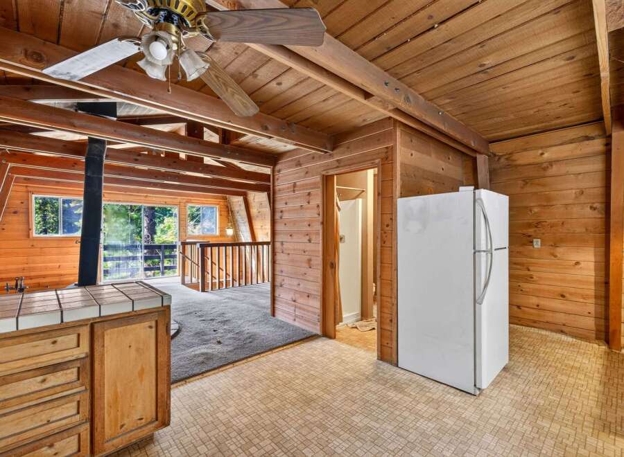 Experience rustic charm in this unique cabin-style kitchen, featuring warm wood paneling throughout and a cozy A-frame ceiling.