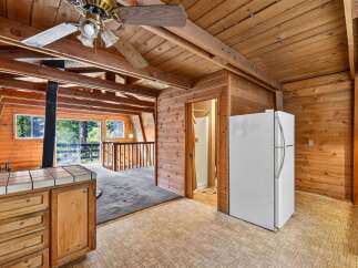 Experience rustic charm in this unique cabin-style kitchen, featuring warm wood paneling throughout and a cozy A-frame ceiling.