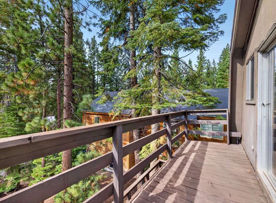 Enjoy the serene mountain views from this charming cabin deck, nestled amongst towering pine trees.