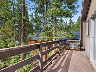 Enjoy the serene mountain views from this charming cabin deck, nestled amongst towering pine trees.