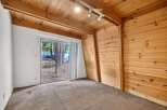 Experience rustic charm in this cozy room featuring warm wood paneling and a sloped wooden ceiling with exposed beams.