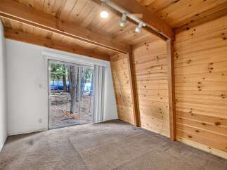 Experience rustic charm in this cozy room featuring warm wood paneling and a sloped wooden ceiling with exposed beams.
