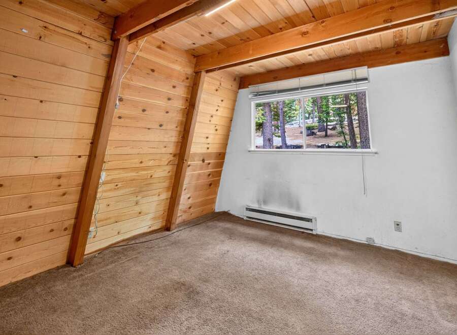 Experience rustic charm in this A-frame style room, featuring warm wood paneling on the walls and ceiling.