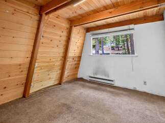 Experience rustic charm in this A-frame style room, featuring warm wood paneling on the walls and ceiling.