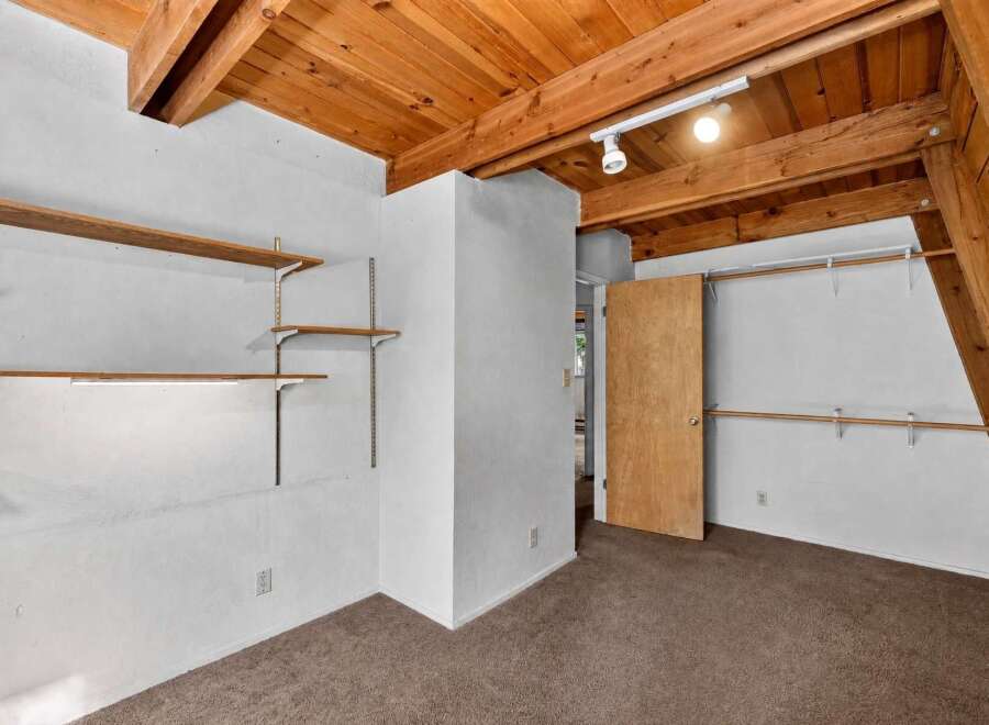 Discover ample storage solutions in this unique room, featuring multiple built-in shelves and closet rods.