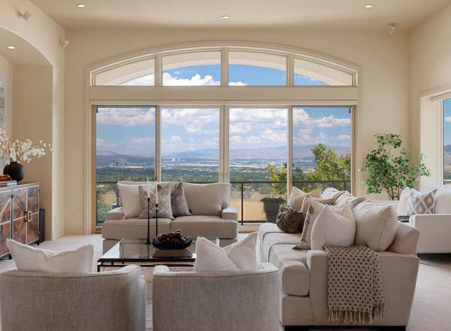 Experience breathtaking panoramic views from this stunning living room, featuring a large sectional sofa and comfortable armchairs perfect for relaxation.
