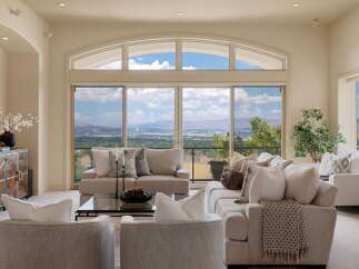 Experience breathtaking panoramic views from this stunning living room, featuring a large sectional sofa and comfortable armchairs perfect for relaxation.