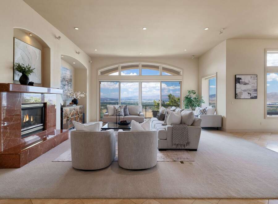 Experience breathtaking panoramic views from this stunning living room, featuring a grand marble fireplace and expansive windows that flood the space with natural light.