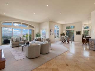 Experience breathtaking panoramic views from this expansive living area, featuring a large sectional sofa and two accent chairs perfect for entertaining.