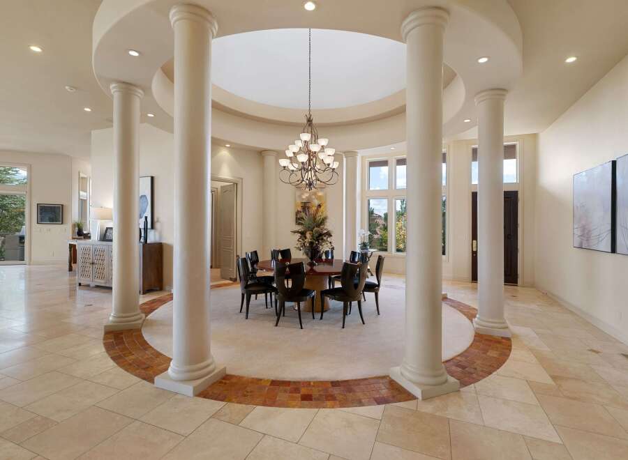 Experience elegant dining in this spacious room, featuring a grand circular dining table with seating for eight, illuminated by a stunning chandelier.
