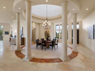 Experience elegant dining in this spacious room, featuring a grand circular dining table with seating for eight, illuminated by a stunning chandelier.