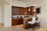 This elegant wet bar features rich cherry wood cabinetry with glass-front upper cabinets, perfect for displaying glassware.