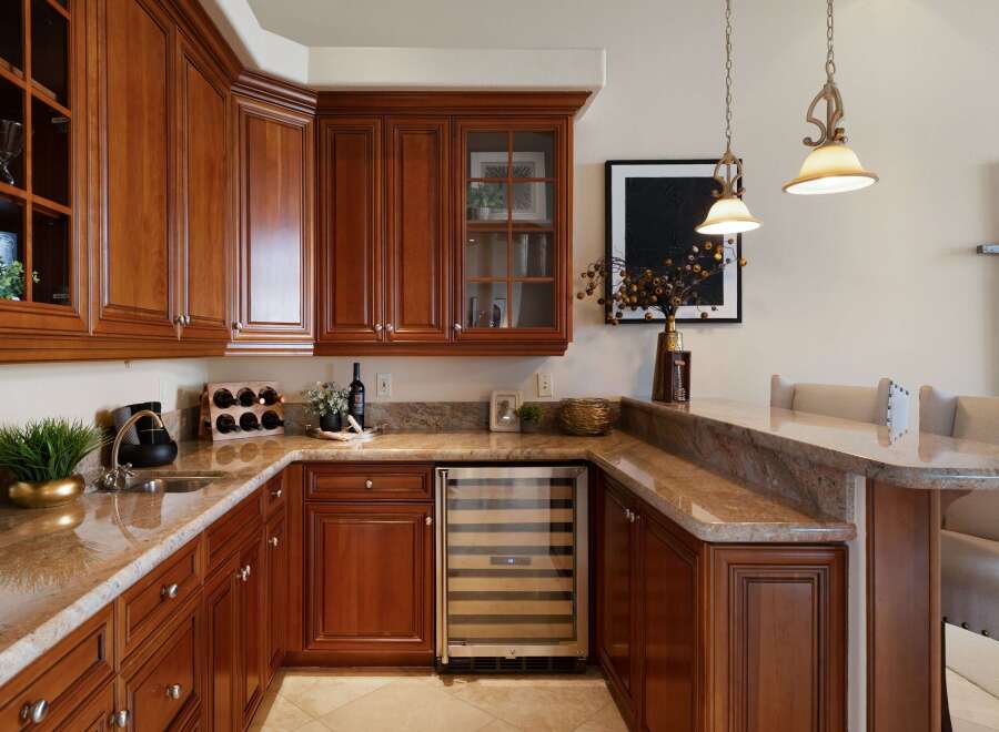 This luxurious wet bar features rich cherry wood cabinetry, granite countertops, and a built-in wine cooler, perfect for entertaining.