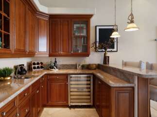 This luxurious wet bar features rich cherry wood cabinetry, granite countertops, and a built-in wine cooler, perfect for entertaining.