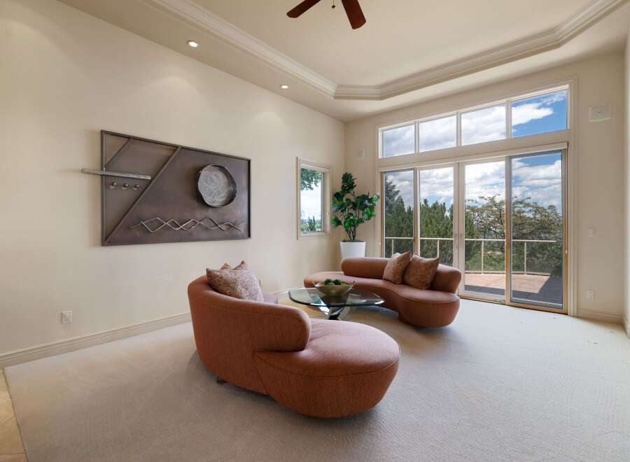 Experience breathtaking views from this stunning living room, featuring a unique curved sofa and a modern metal wall art.