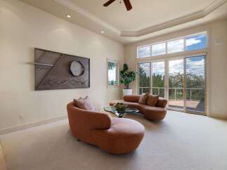 Experience breathtaking views from this stunning living room, featuring a unique curved sofa and a modern metal wall art.