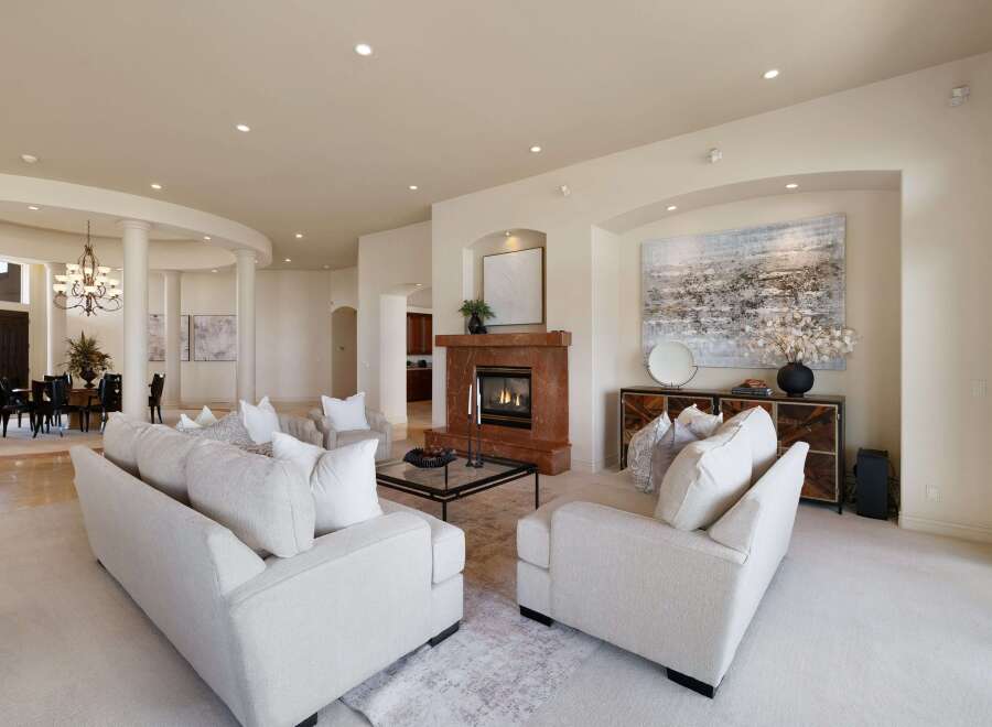 Step into this luxurious living room, featuring plush white sofas and a striking marble fireplace.