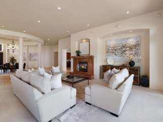Step into this luxurious living room, featuring plush white sofas and a striking marble fireplace.
